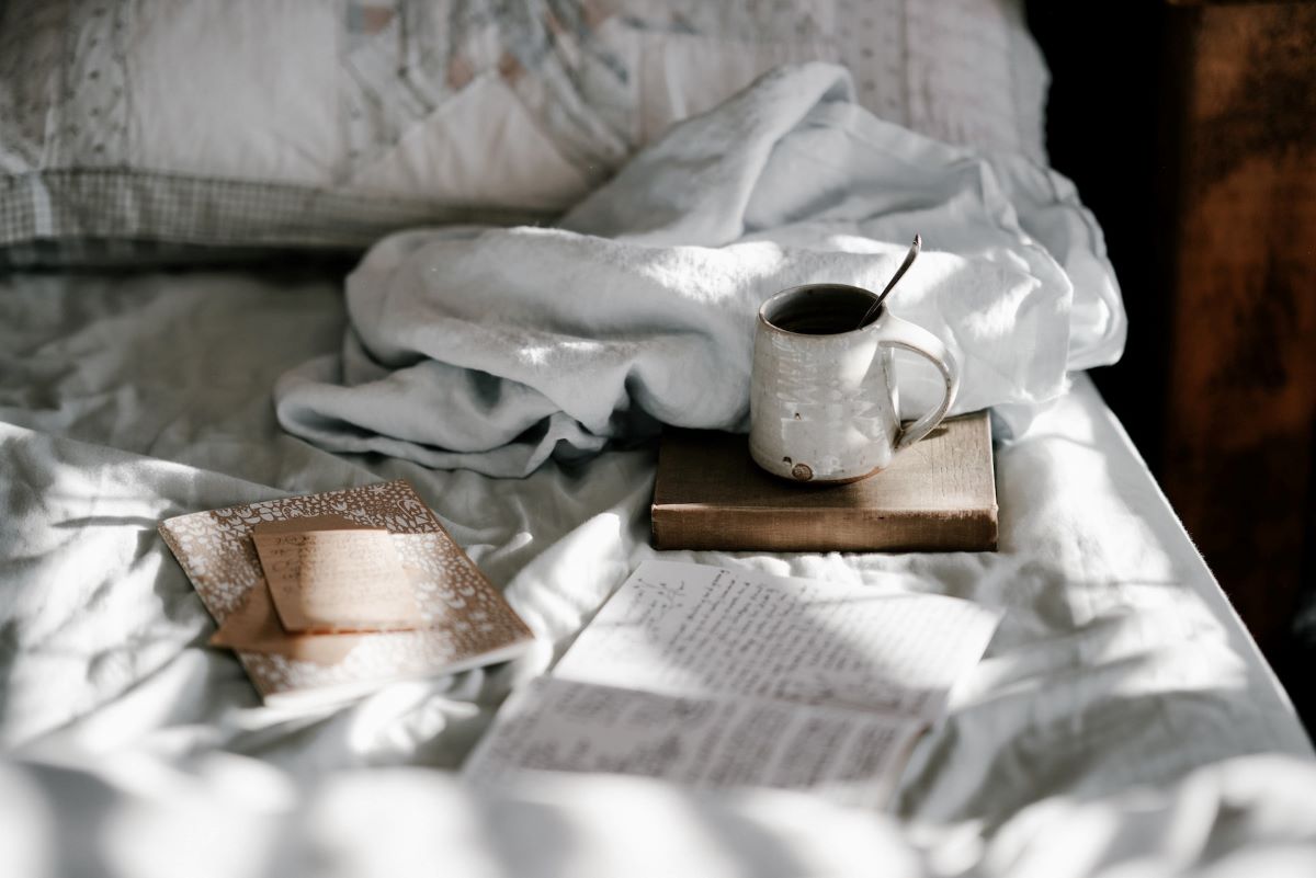 a cozy bed with journals and coffee where someone learned how to relax as a teacher