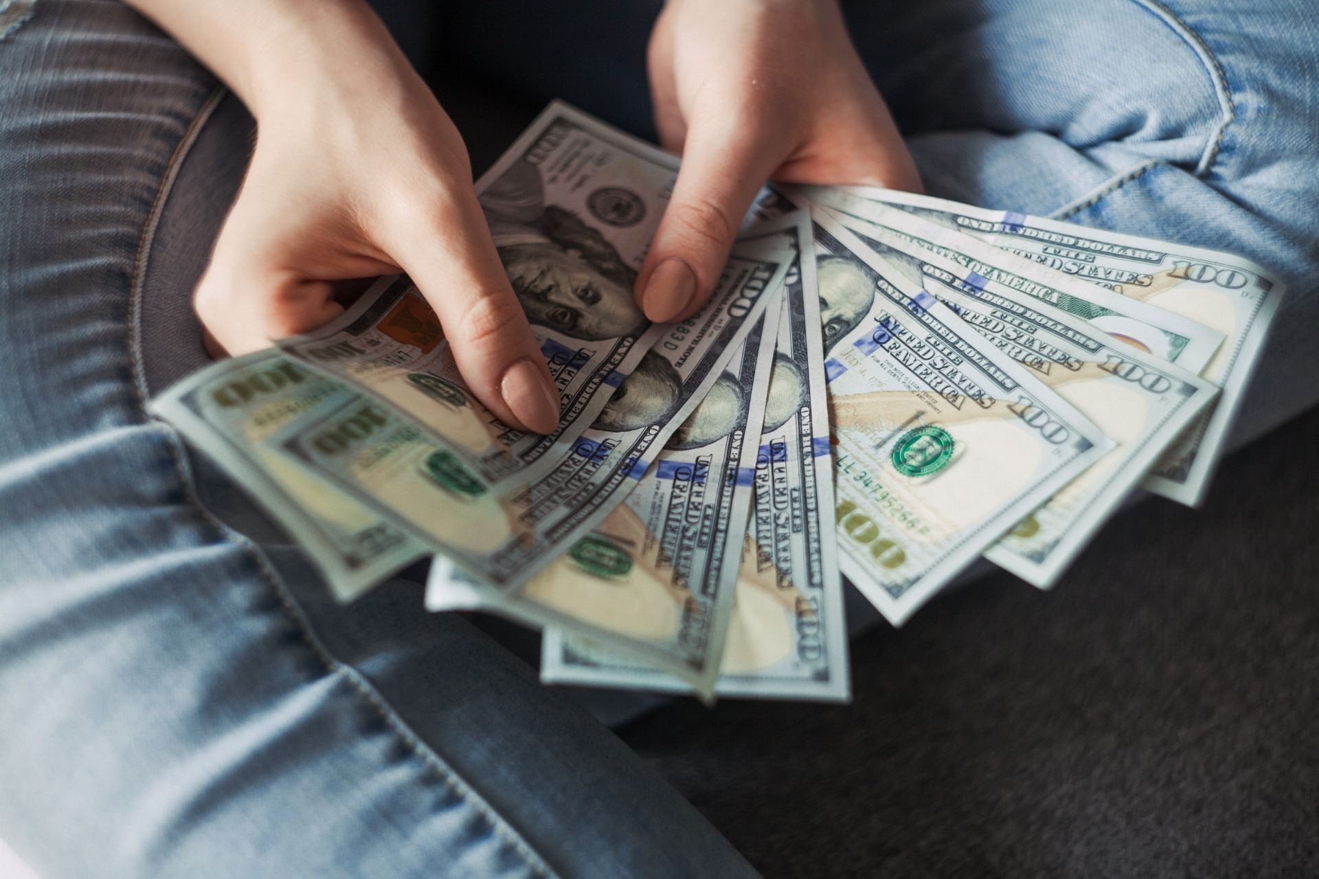 Hand holding a spread of dollar bills, graphic designer's salary